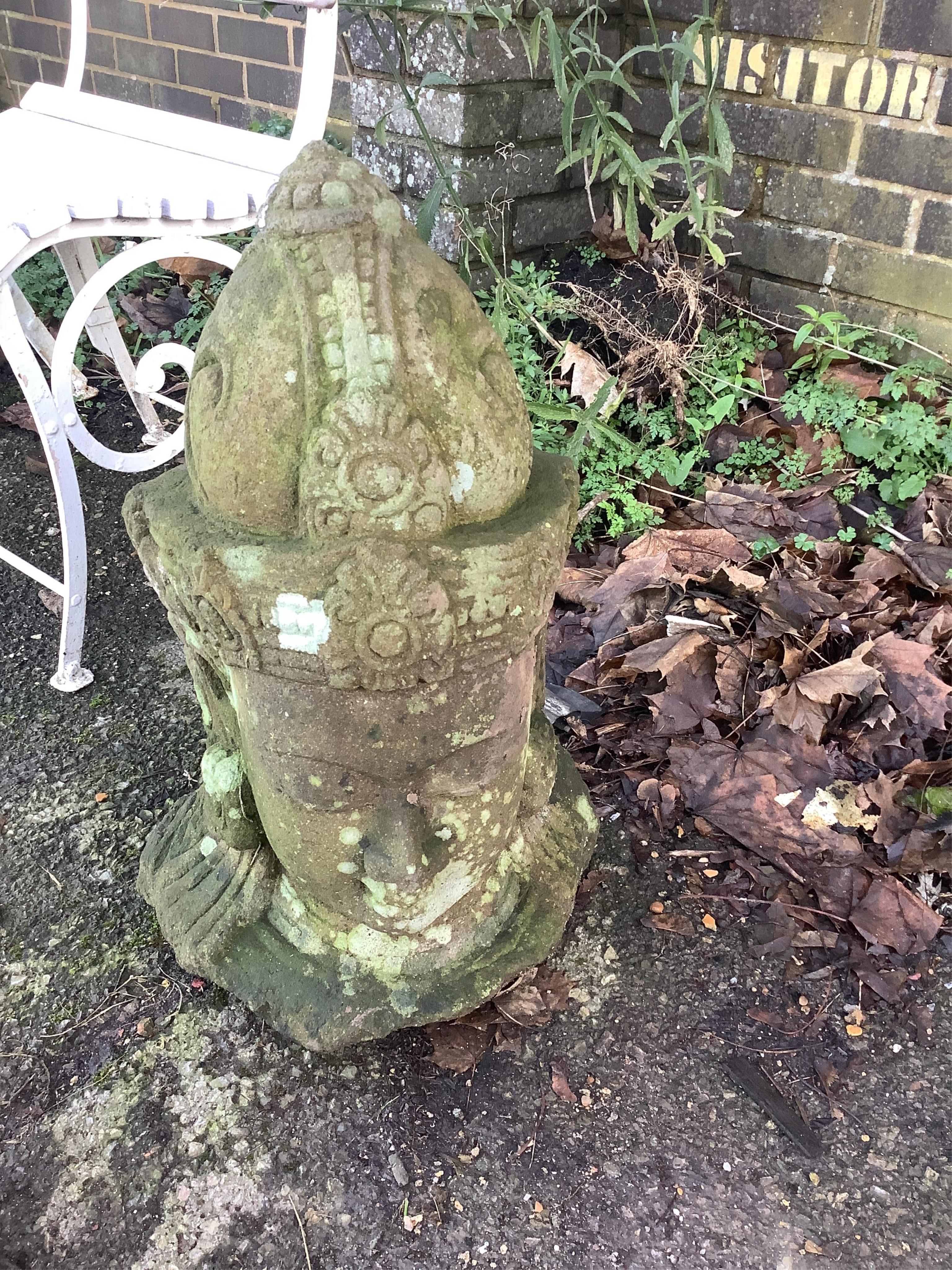 A weathered carved stone head of Buddha, raised on a square stepped base, height 58cm. Condition - fair